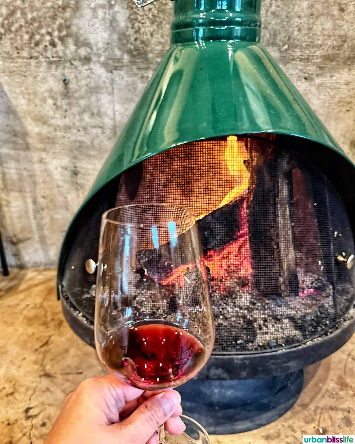 glass of red wine in front of a green fireplace.