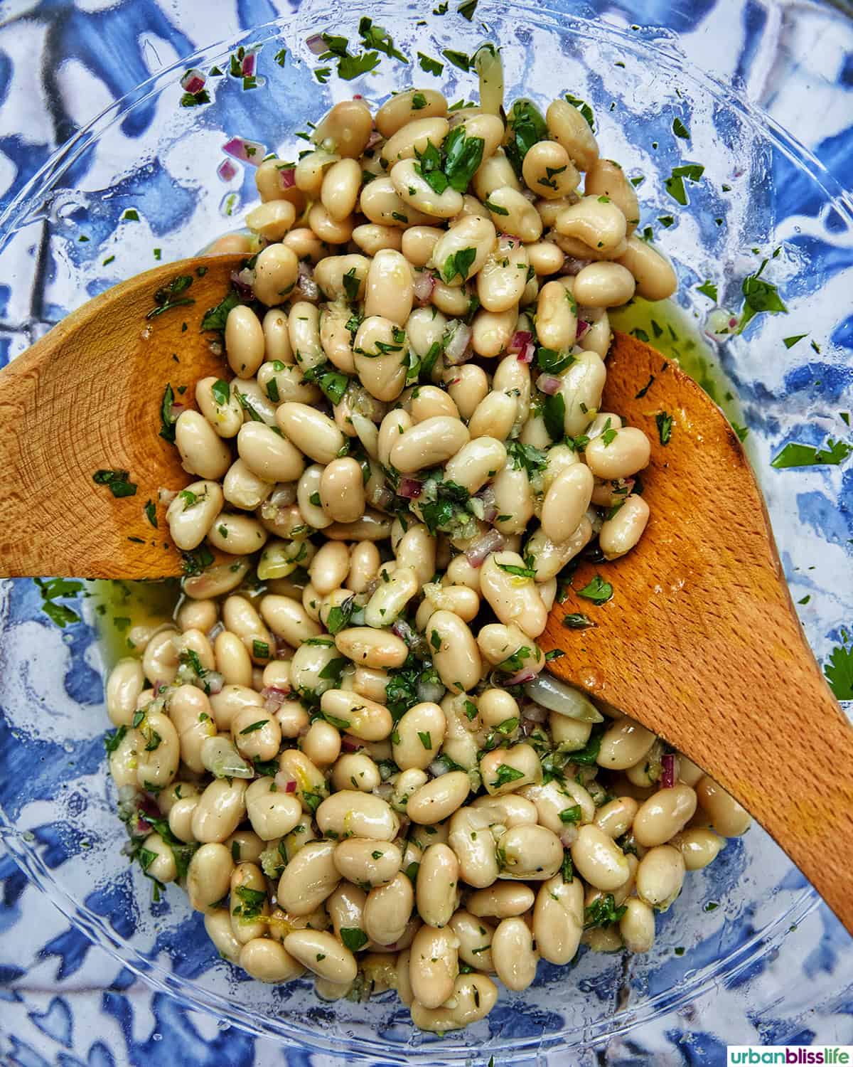 wooden spoons in a bowl of white bean salad.