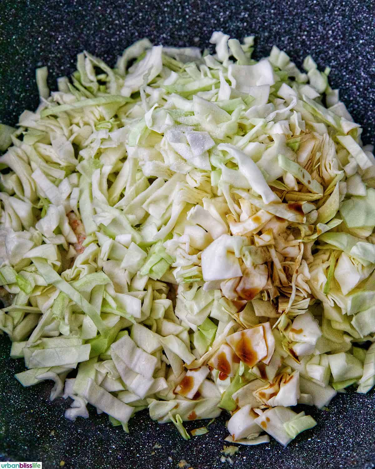 shredded cabbage added to a wok.