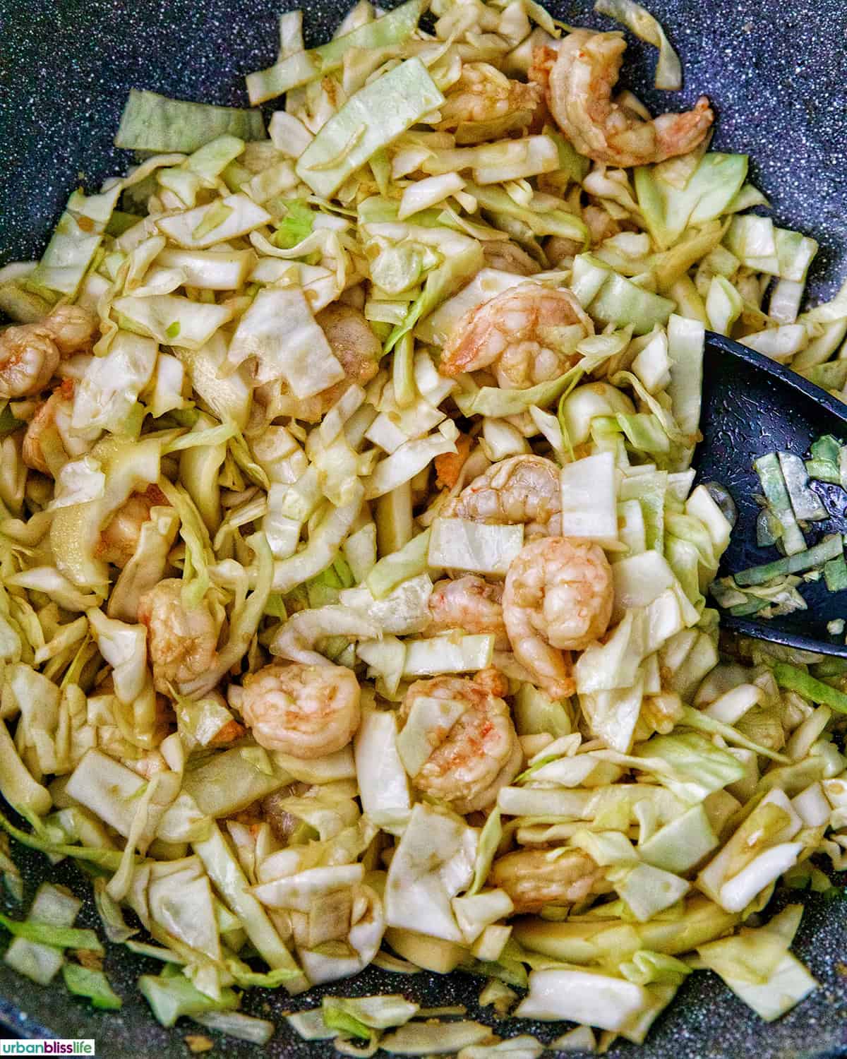 cabbage and shrimp stir fry in a wok.