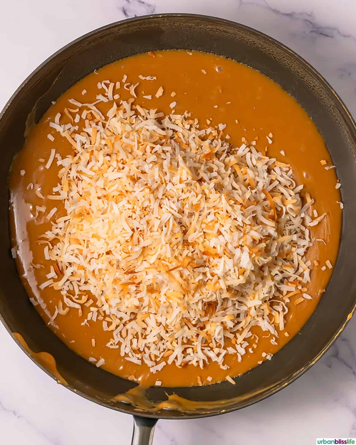 toasted shredded coconut over melted caramel in a pan.