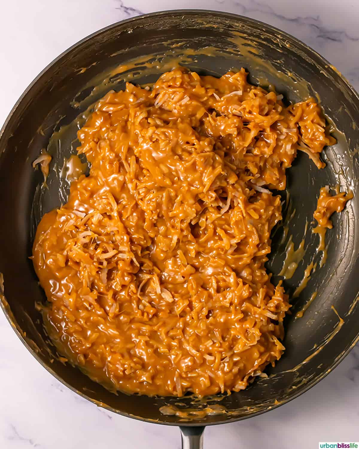 shredded coconut mixed with melted caramel in a pan.