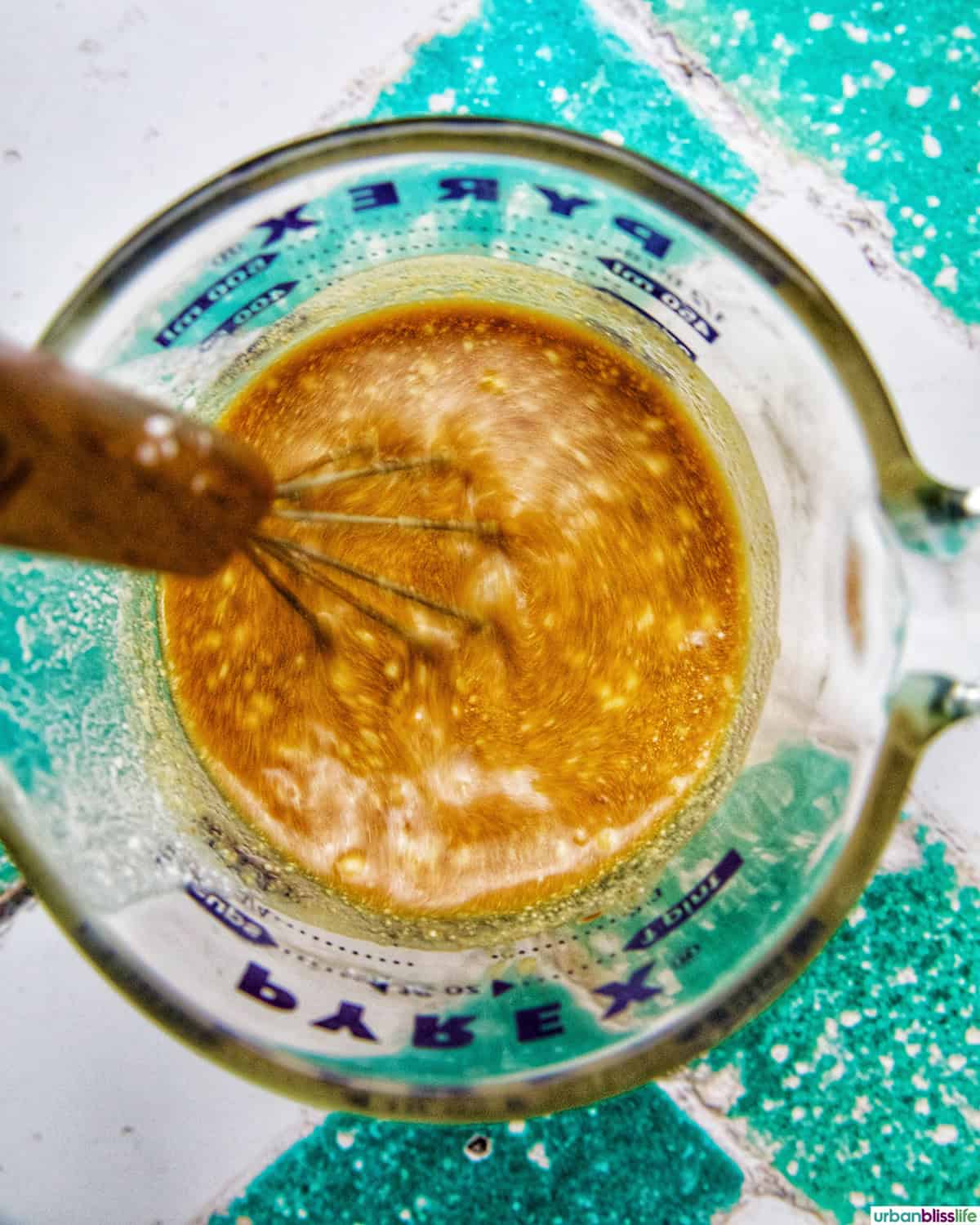 Asian marinade and sauce in a glass container with whisk.