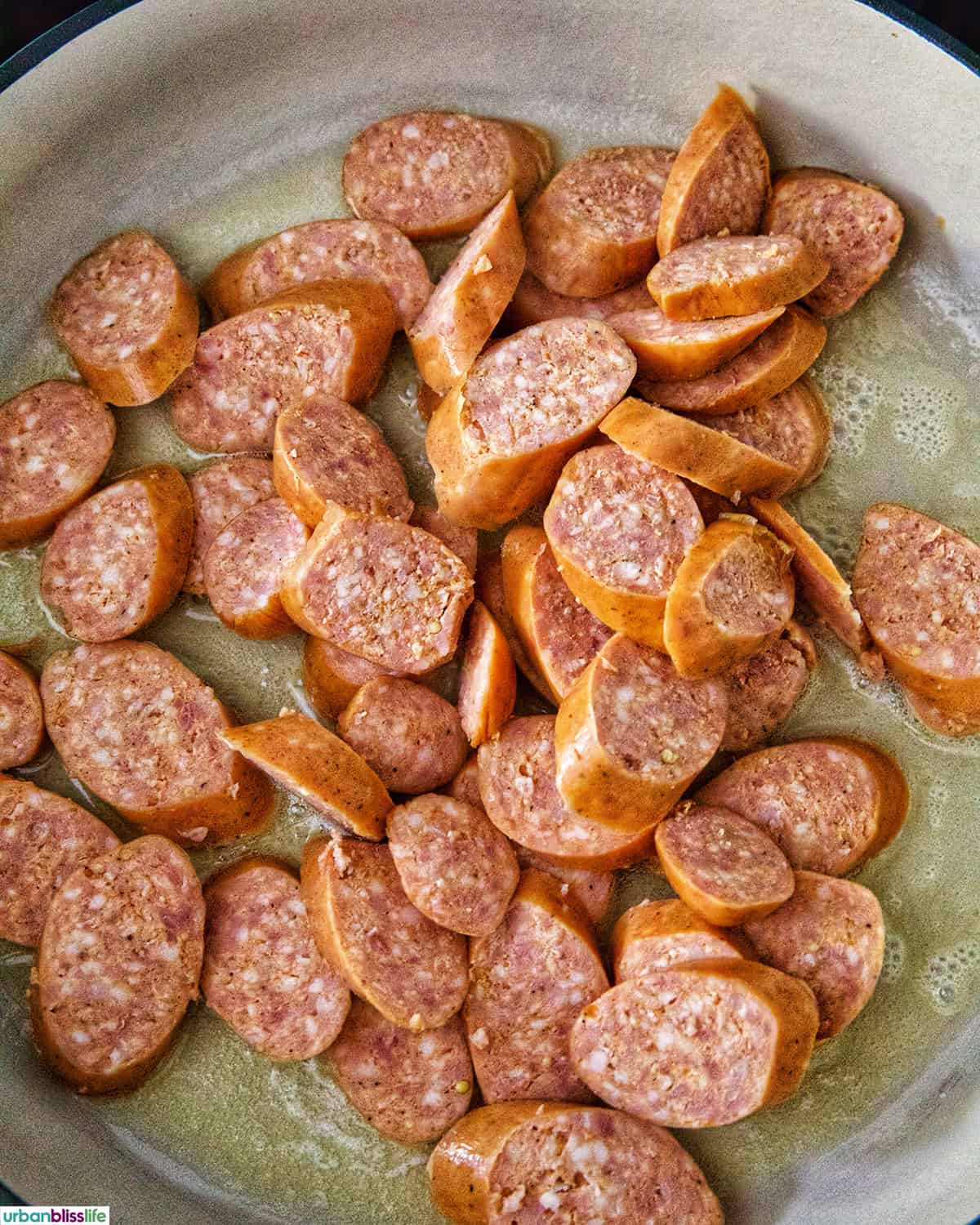 sliced kielbasa sausage in a skillet cooking.