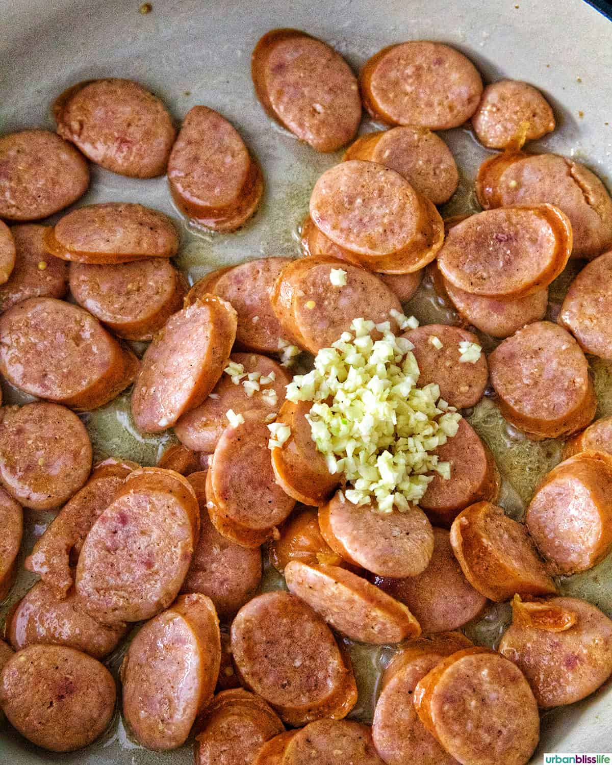 minced garlic and sausage in a white pan.