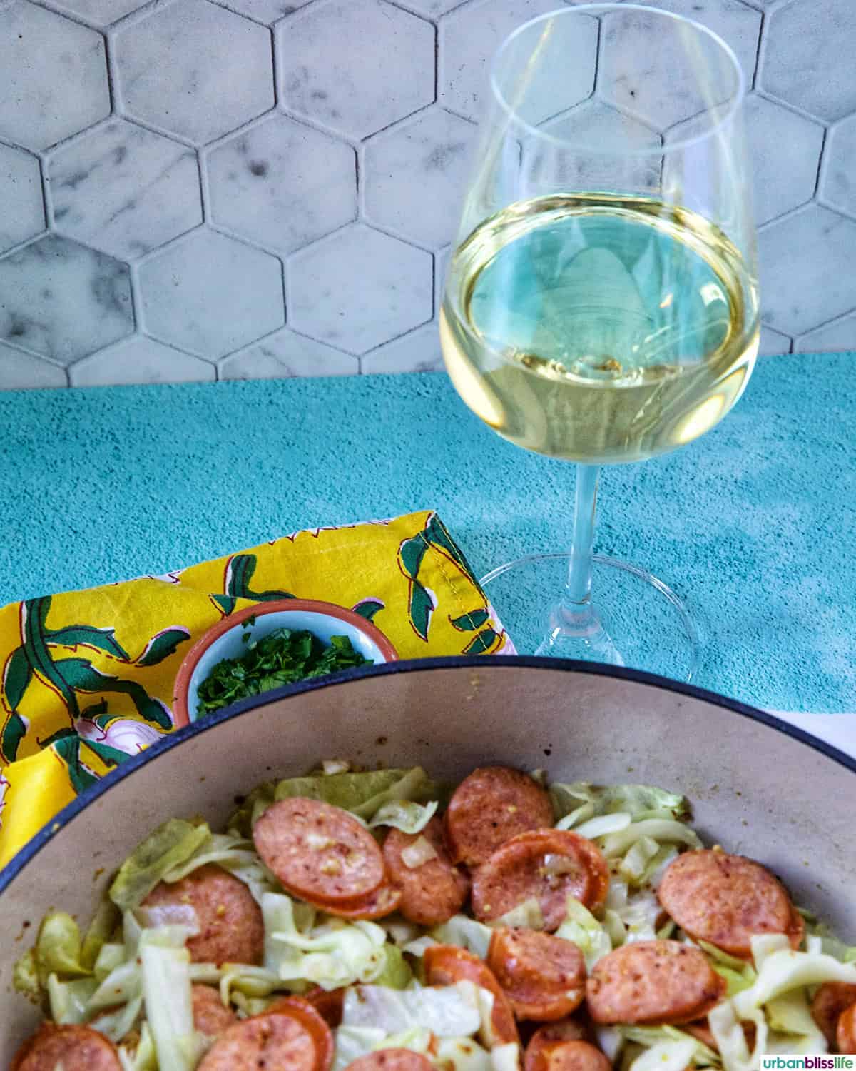Glass of white wine with Sausage and Cabbage skillet.