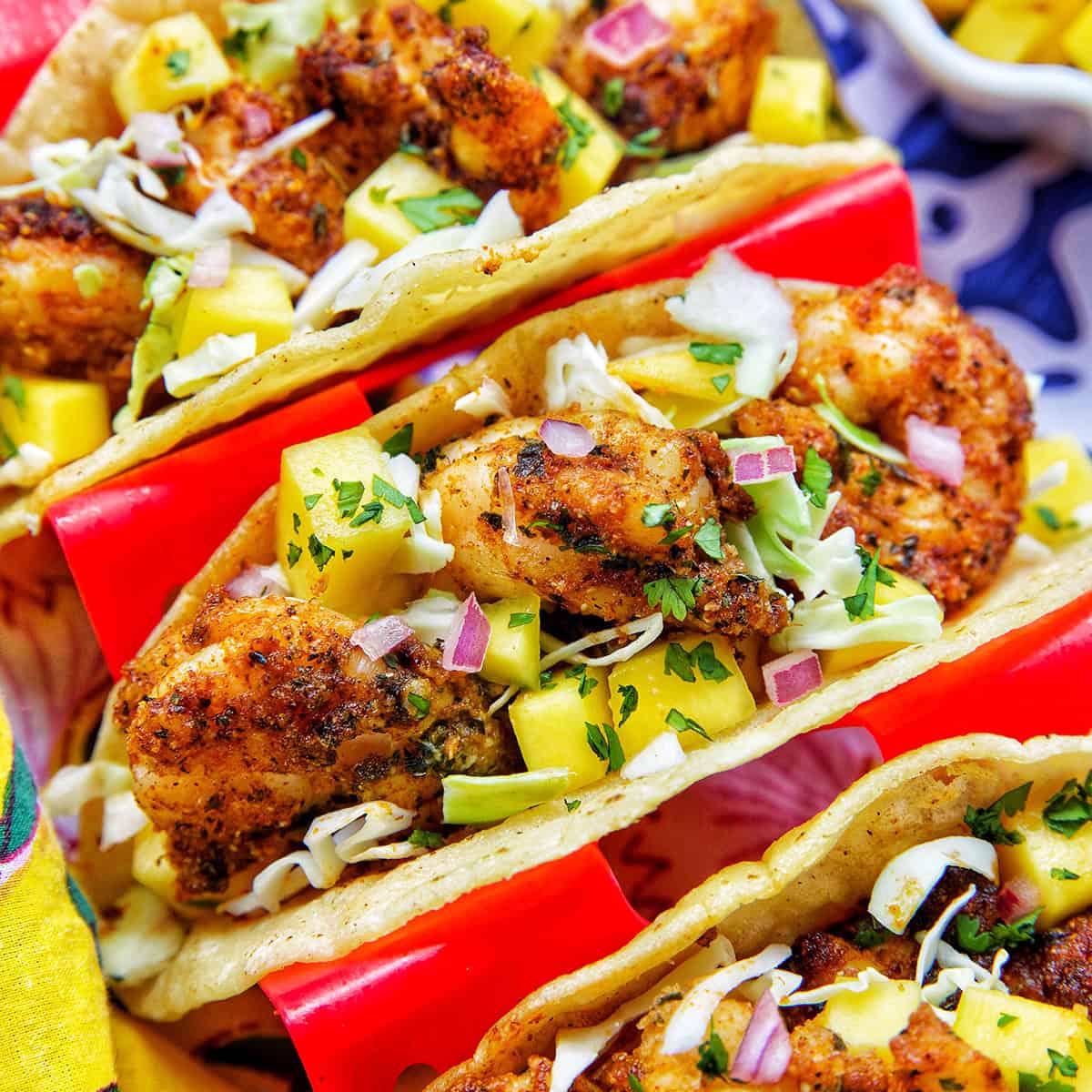 three air fryer shrimp tacos in a red taco stand.