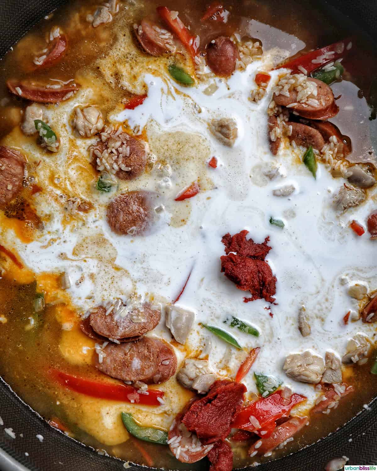 coconut milk added to Arroz a la Valenciana in a skillet.