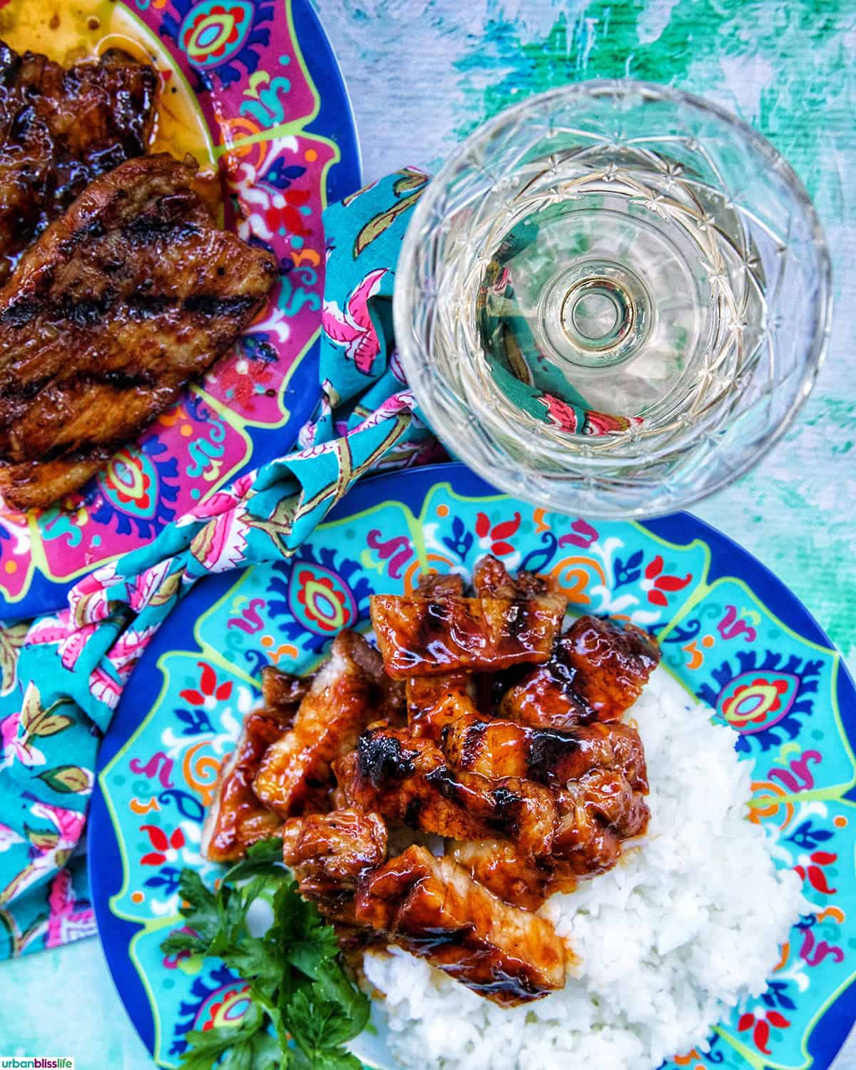 colorful plate of Filipino grilled pork belly and rice with white wine glass.