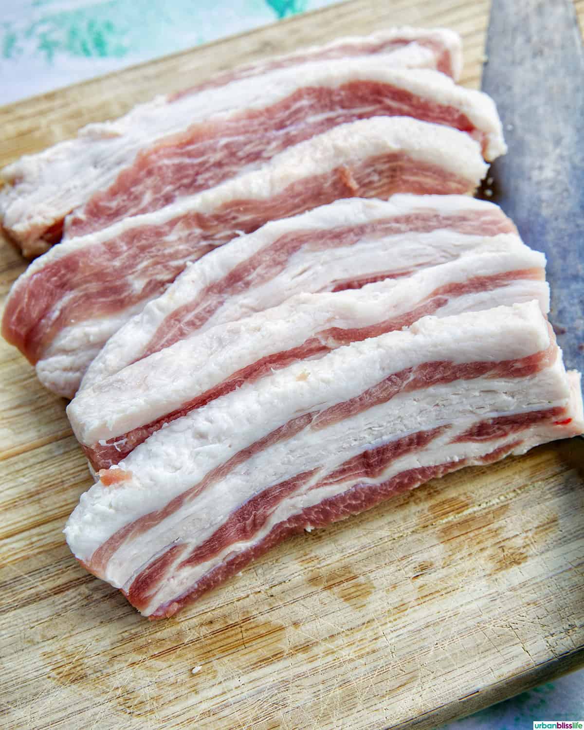 sliced pork belly on a cutting board.