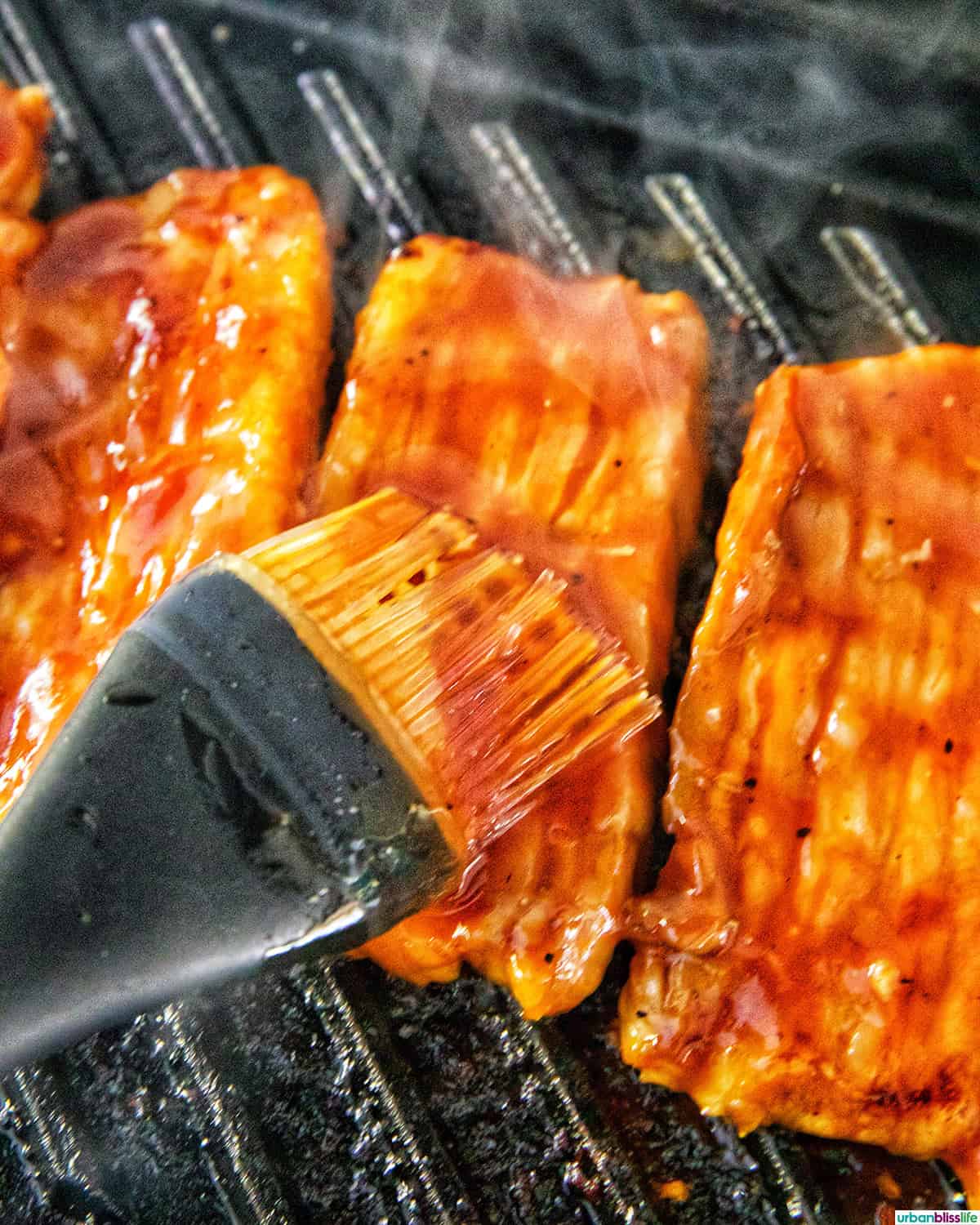 brushing marinade on Filipino grilled pork belly on a grill pan.