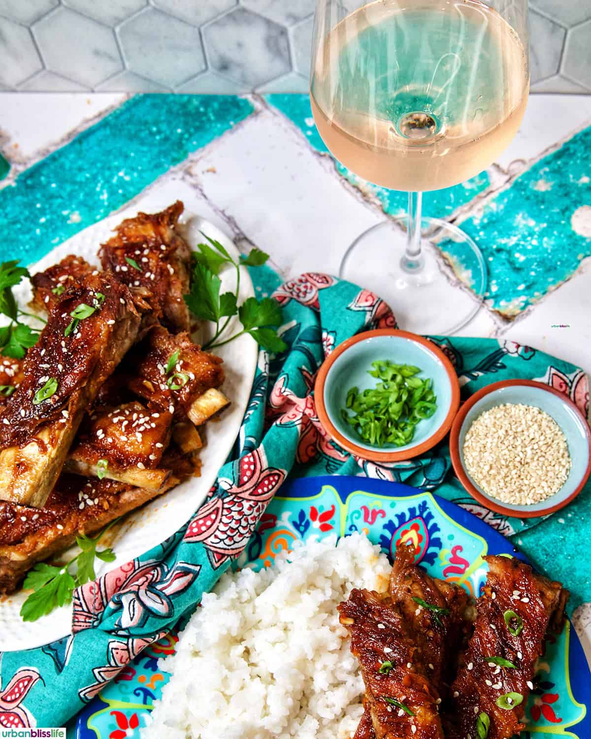 Instant Pot Asian Sticky Pork Ribs on two plates with a glass of rosé wine.