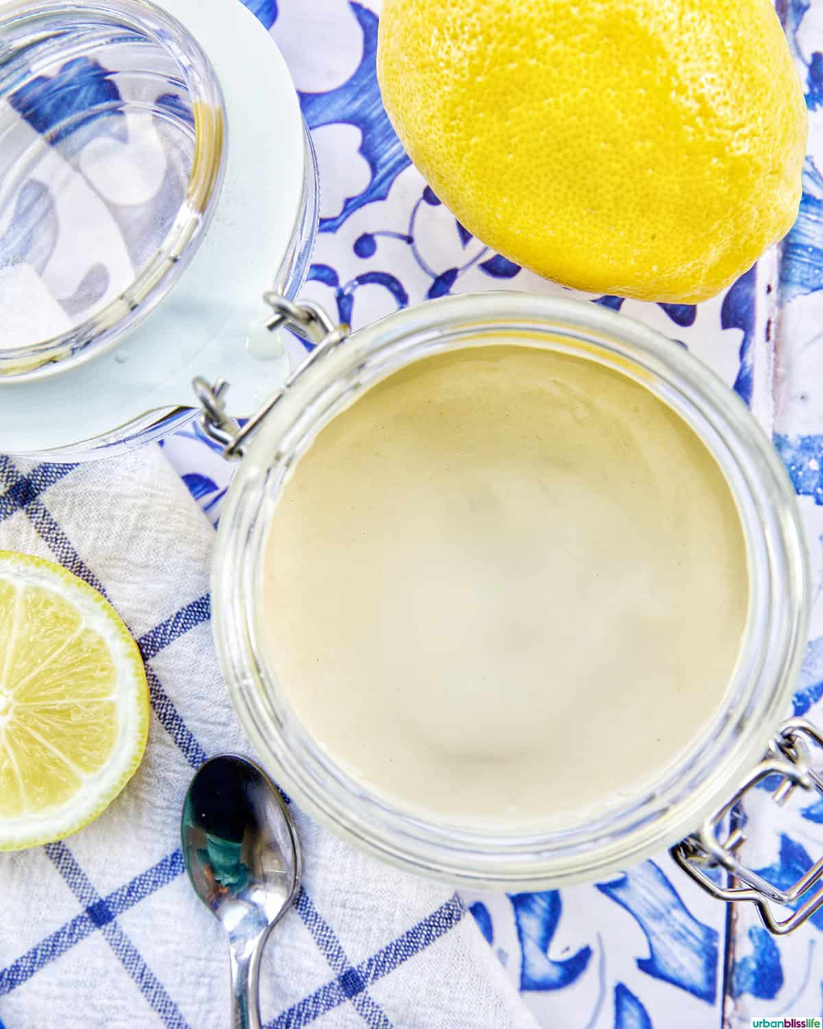 jar of lemon tahini dressing with sides of cut lemons.