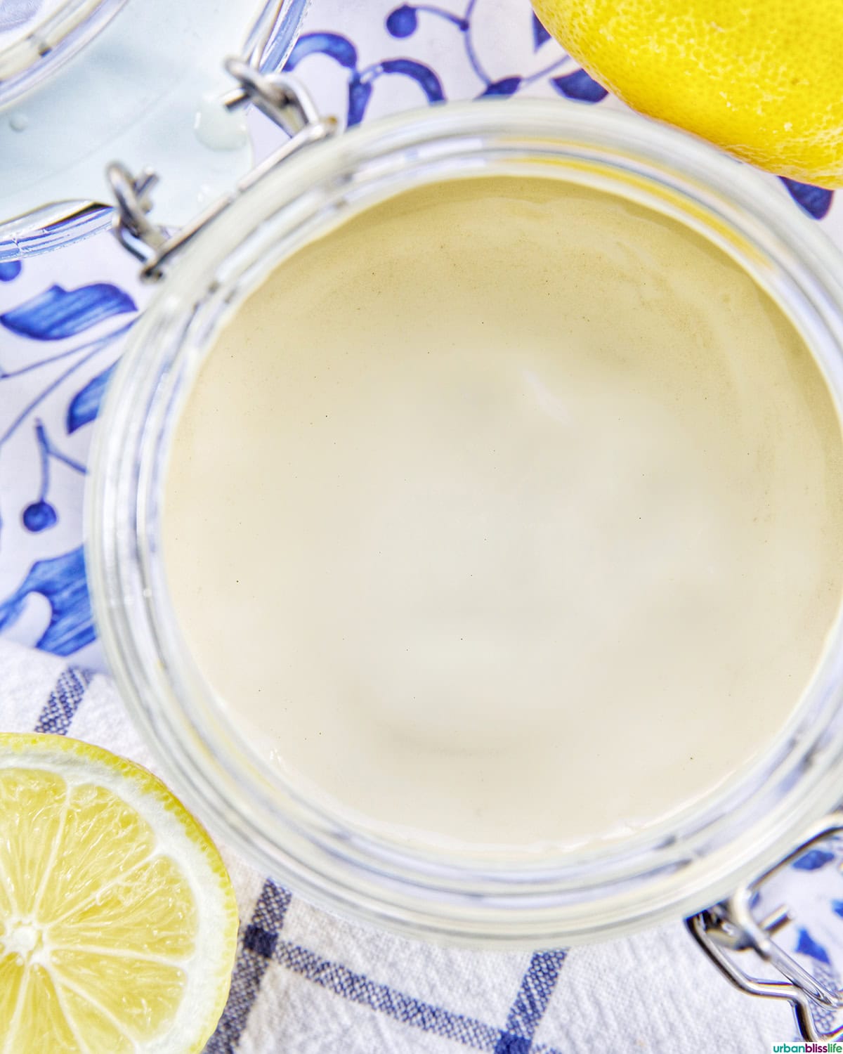 jar of lemon tahini dressing with sides of cut lemons.