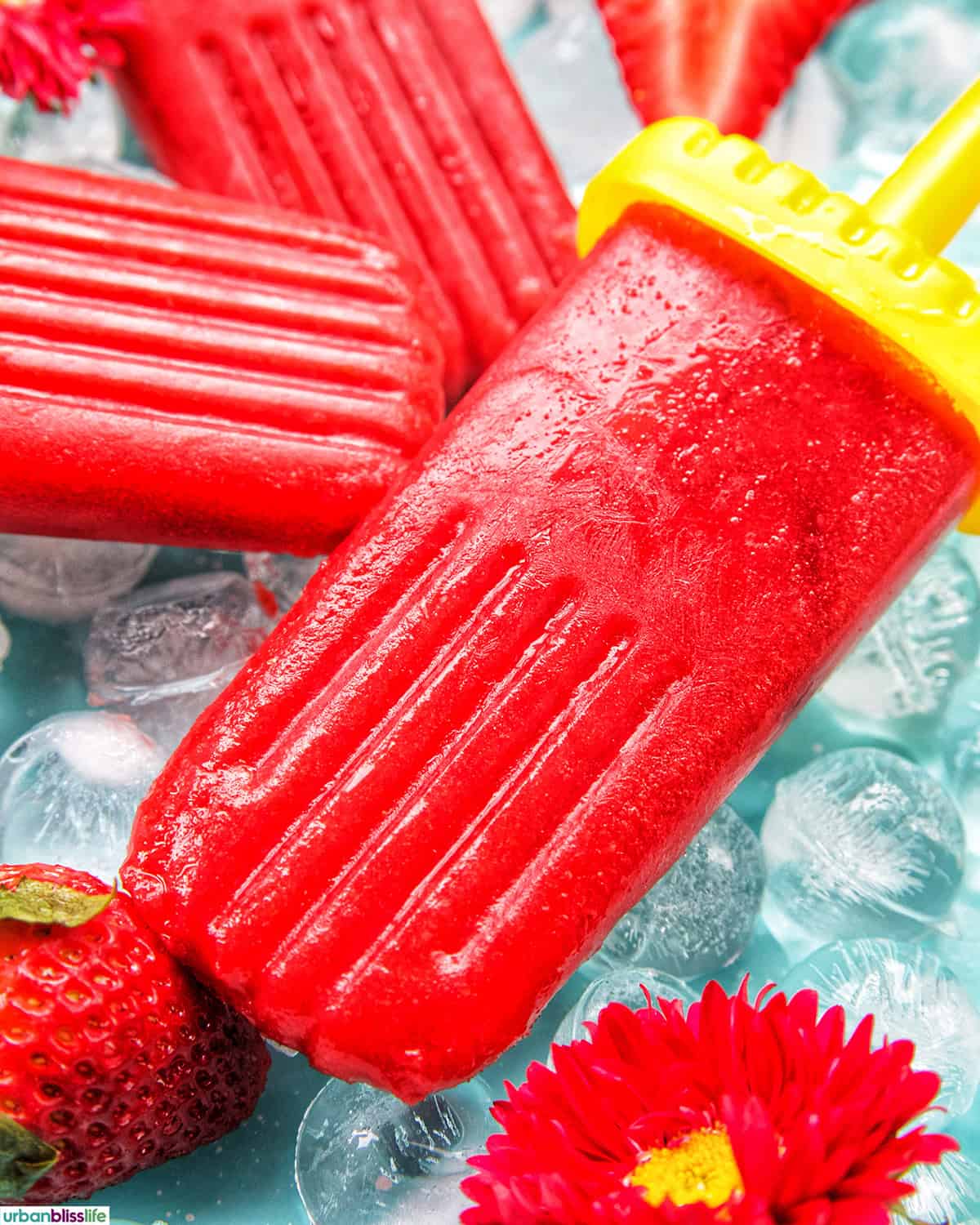 three strawberry fruit popsicles on ice