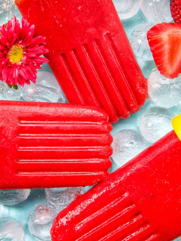 three strawberry fruit popsicles on ice