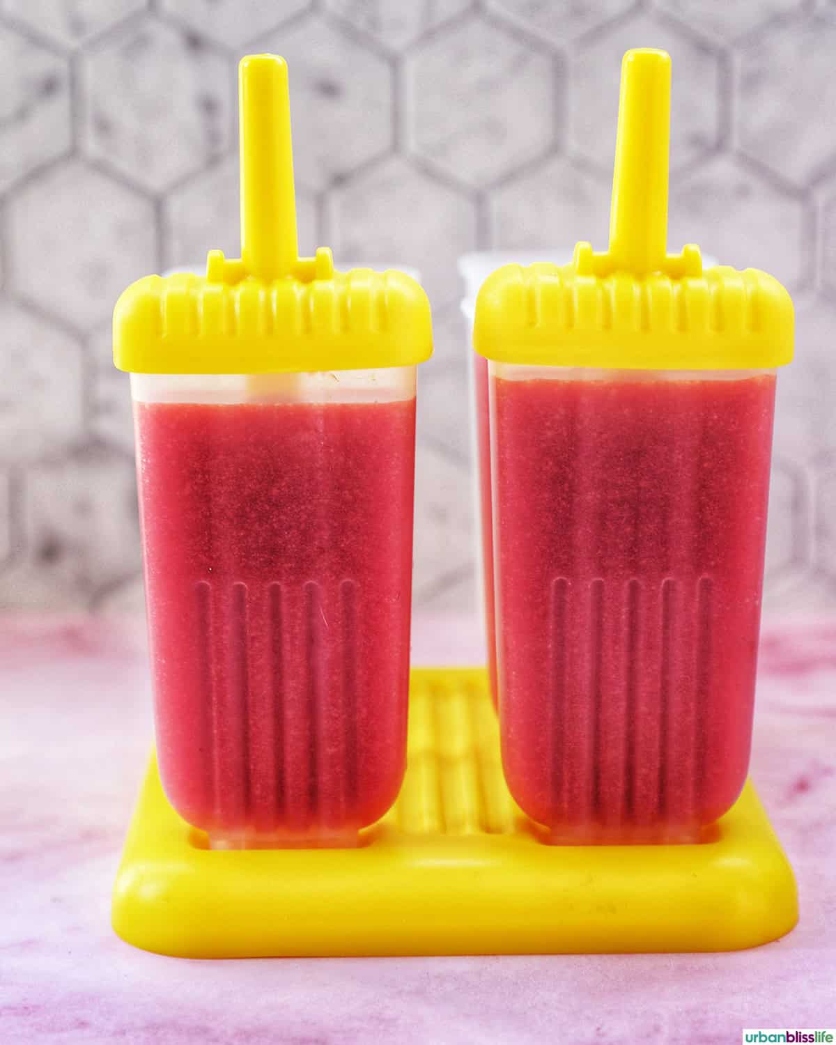 two strawberry fruit popsicles in popsicle molds.