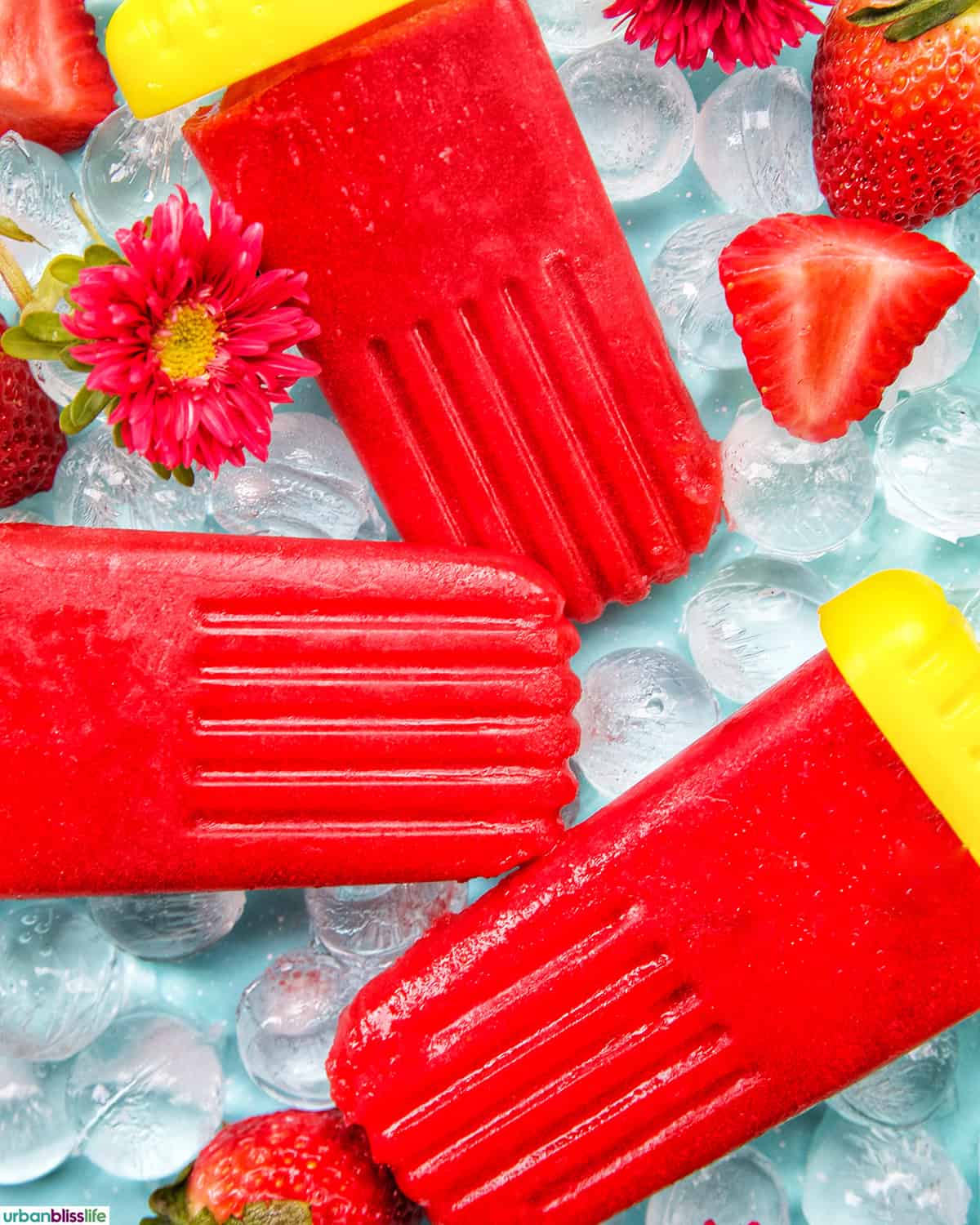 three strawberry fruit popsicles on ice.