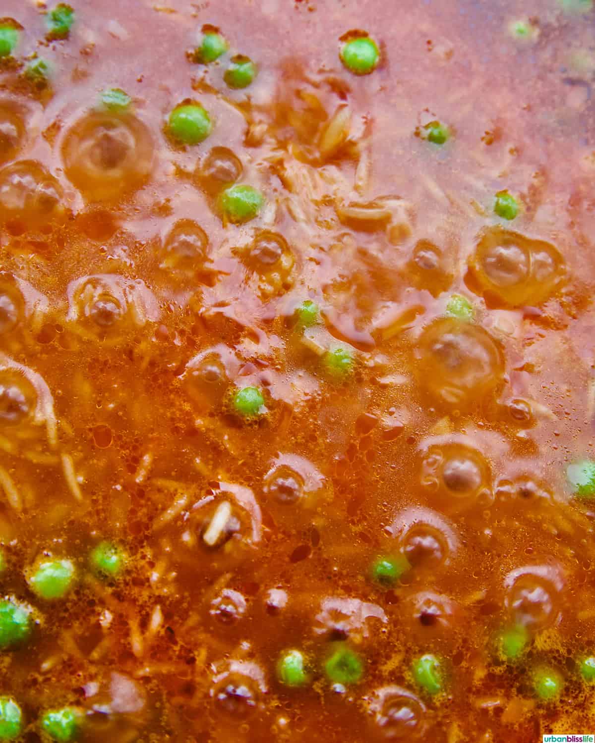 vegetarian Mexican rice and peas in a skillet, coming to a boil.