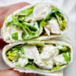 hand holding a Chicken Caesar Salad Wrap sliced in half.