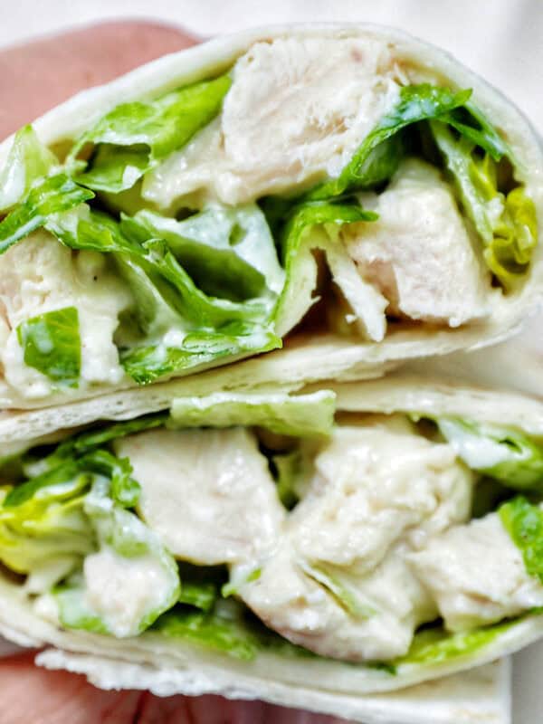 hand holding a Chicken Caesar Salad Wrap sliced in half.