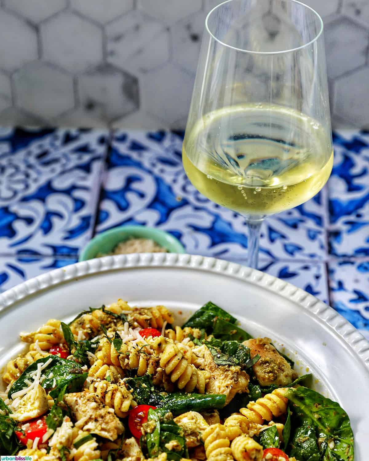 bowl of chicken pesto pasta salad with a glass of white wine.