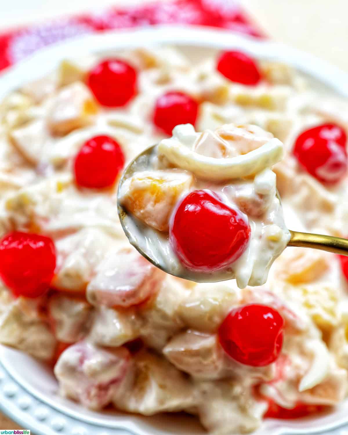 spoon of bowl of Filipino Fruit Salad topped with maraschino cherries.