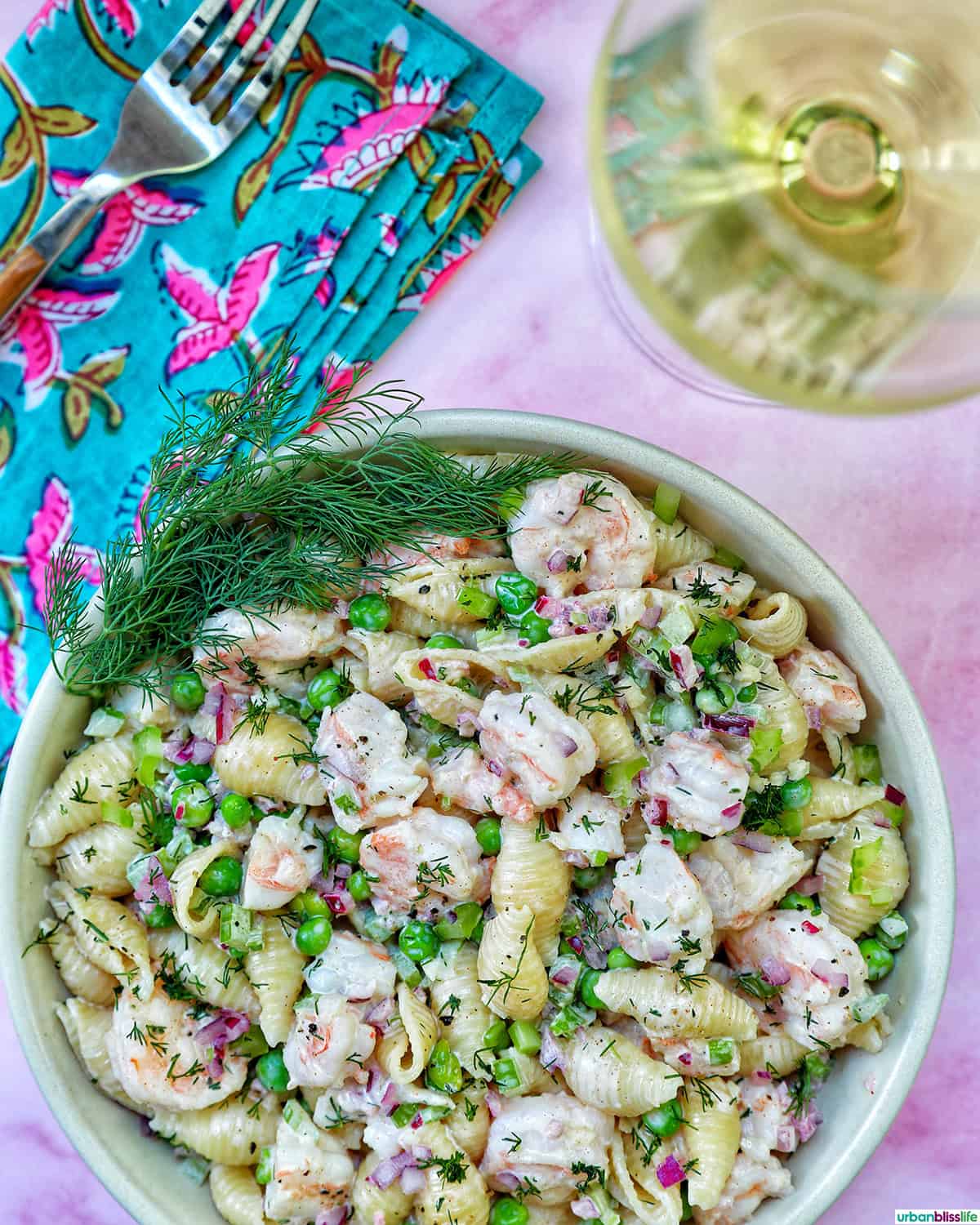 bowl of shrimp pasta salad with a glass of white wine.