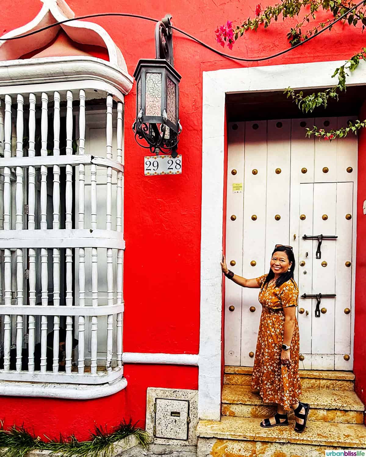 Marlynn in front of a white door and red building.