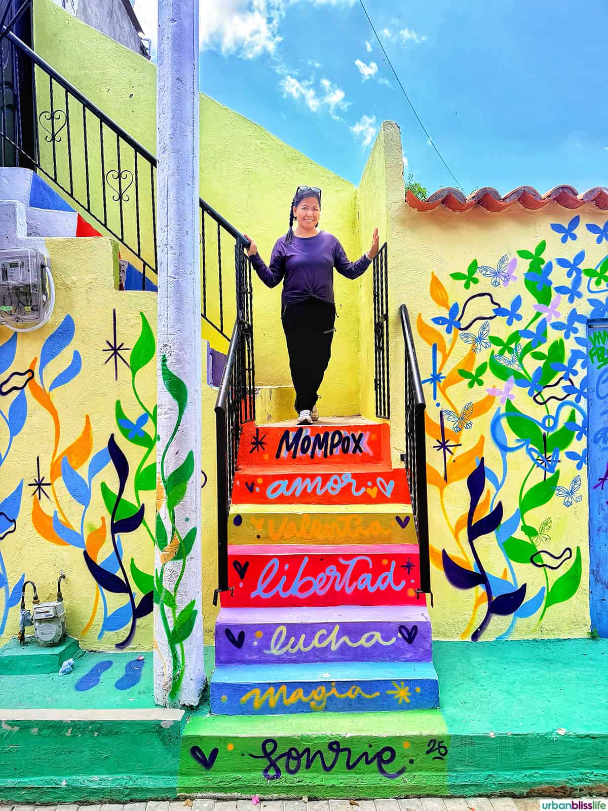 Marlynn standing on colorful painted steps in Santa Cruz de Mompox, Colombia.