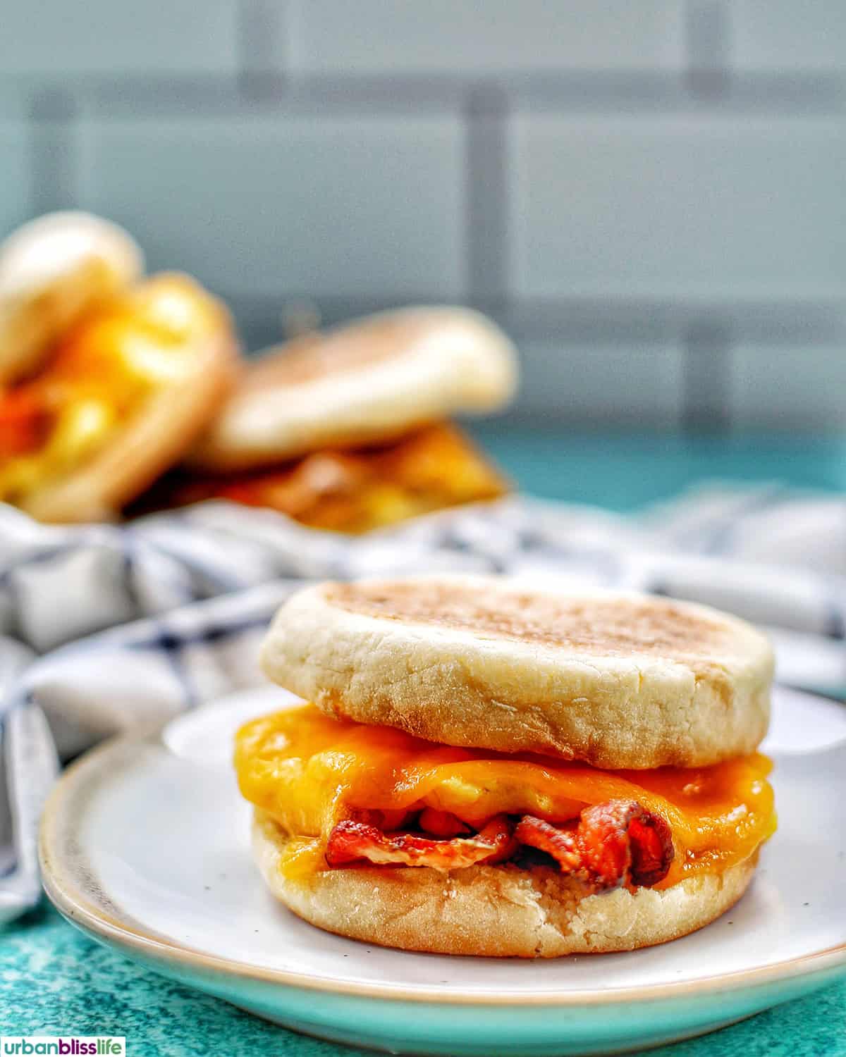 air fryer breakfast sandwich on a plate with two sandwiches in the background.