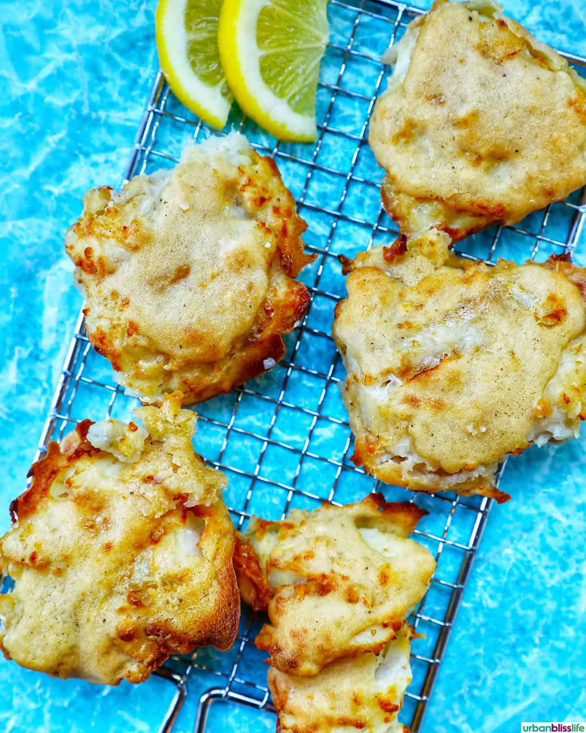 air fryer cod pieces on a fish grid with lemon wedges.