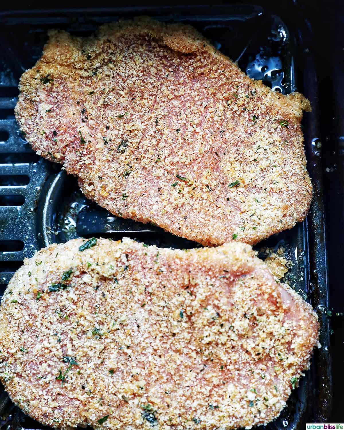 uncooked air fryer shake and bake pork chops in an air fryer basket.