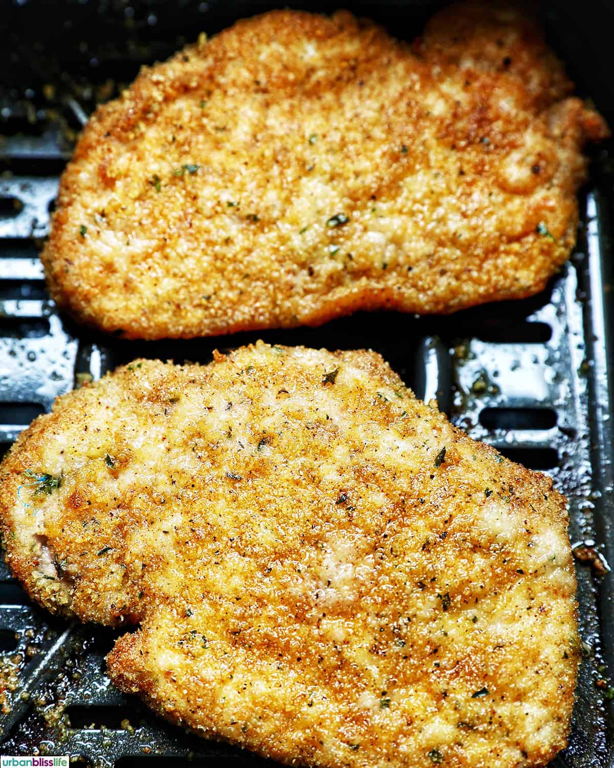 air fryer shake and bake pork chops cooked in the air fryer basket.