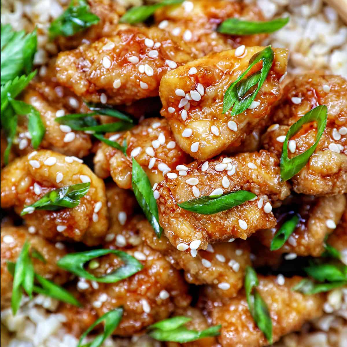 Air fryer teriyaki chicken over brown rice with herbs and chopsticks.