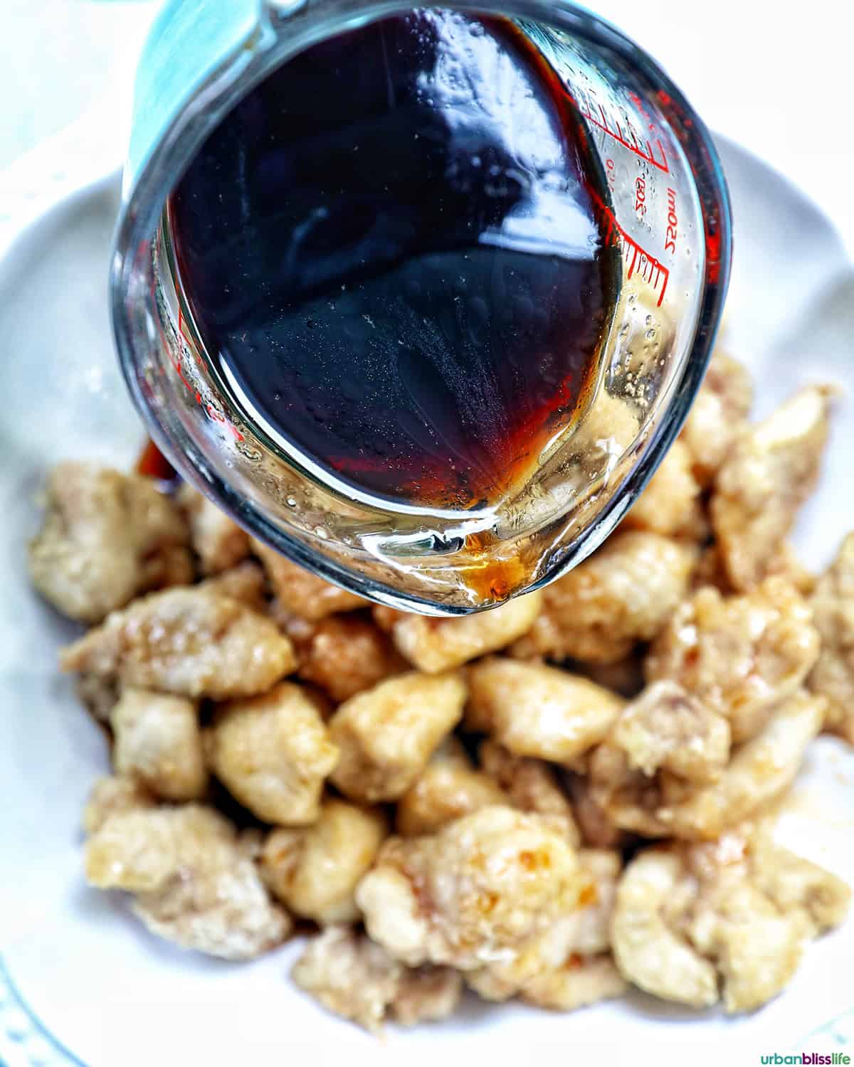 teriyaki sauce about to be poured over air fryer teriyaki chicken in a bowl.