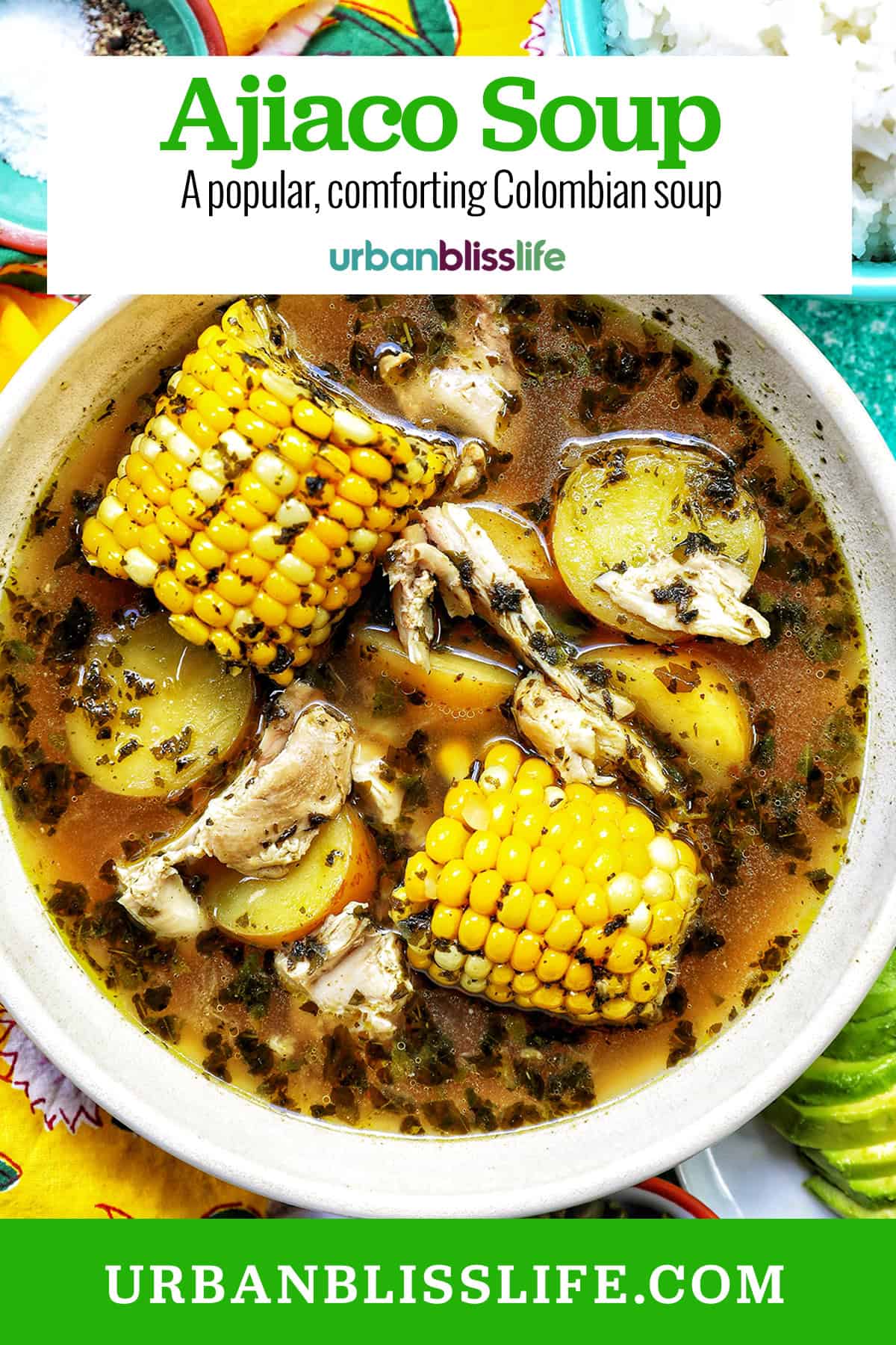 bowl of Colombian Ajiaco soup with corn on the cob and chicken, and sides of rice, avocado slices, capers, and sour cream with title text overlay.