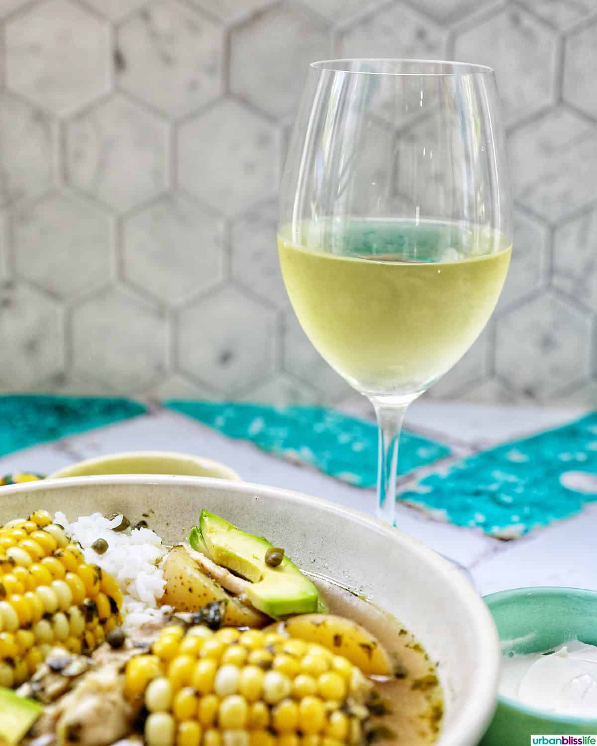 bowl of Colombian Ajiaco soup with a glass of white wine.