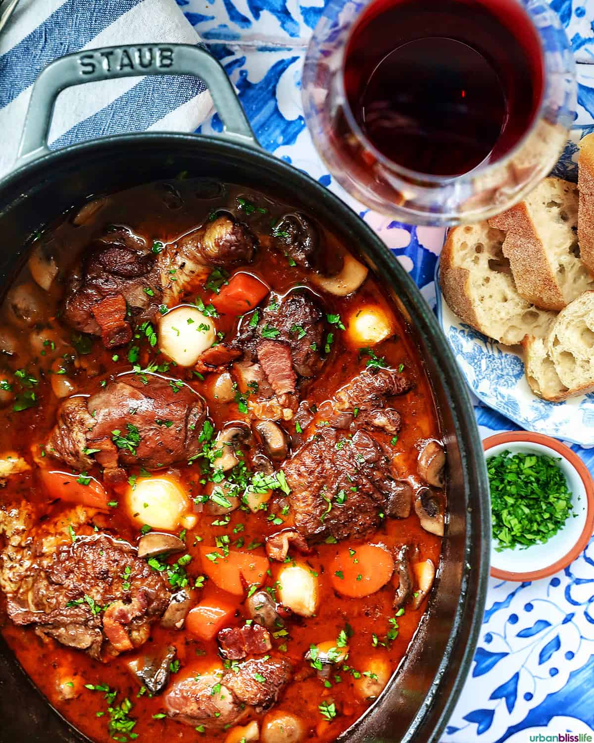 coq au vin in a dutch oven with glass of red wine.