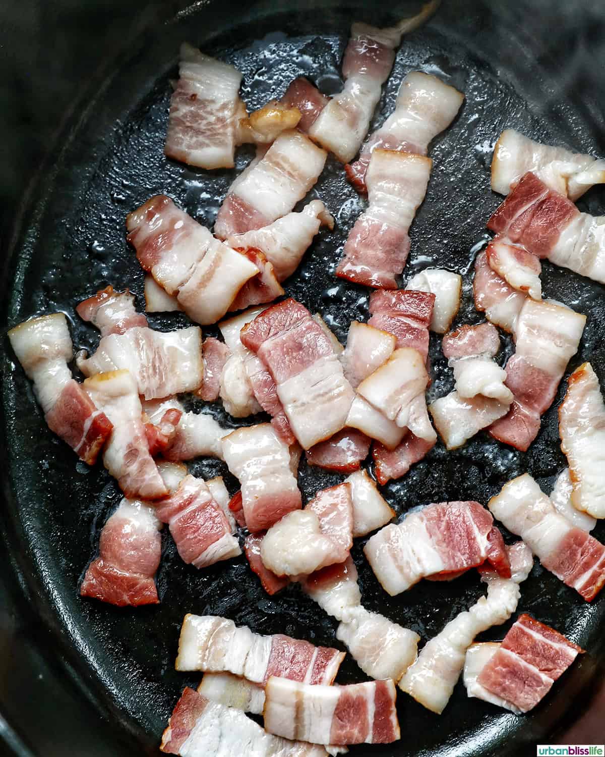 slices of raw bacon cooking in a dutch oven.