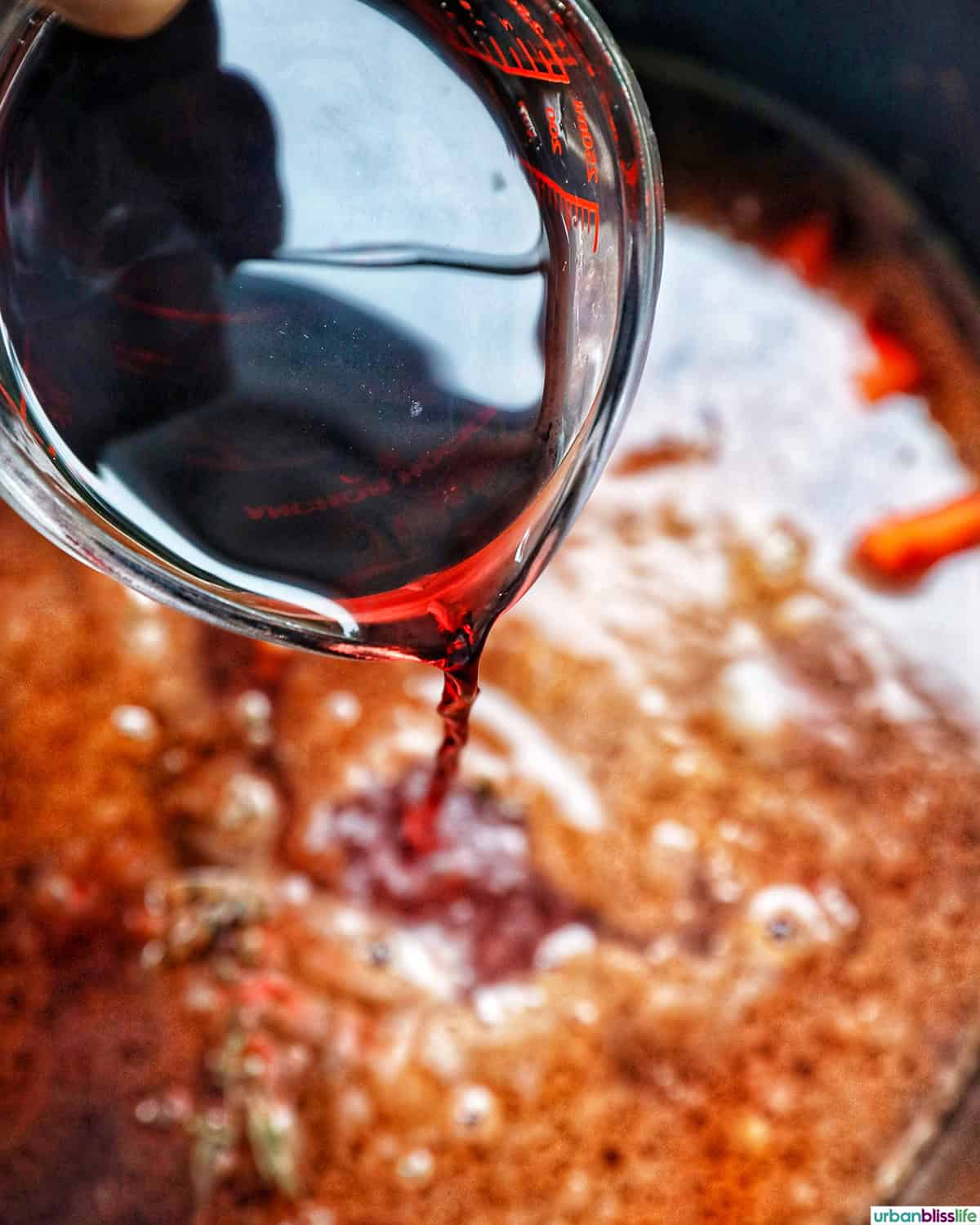 adding red wine to a sauce to make coq au vin
