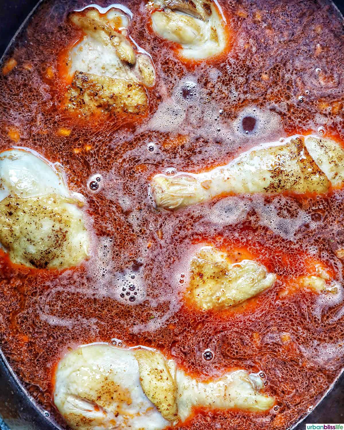 chicken cooking in red wine sauce to make coq au vin.