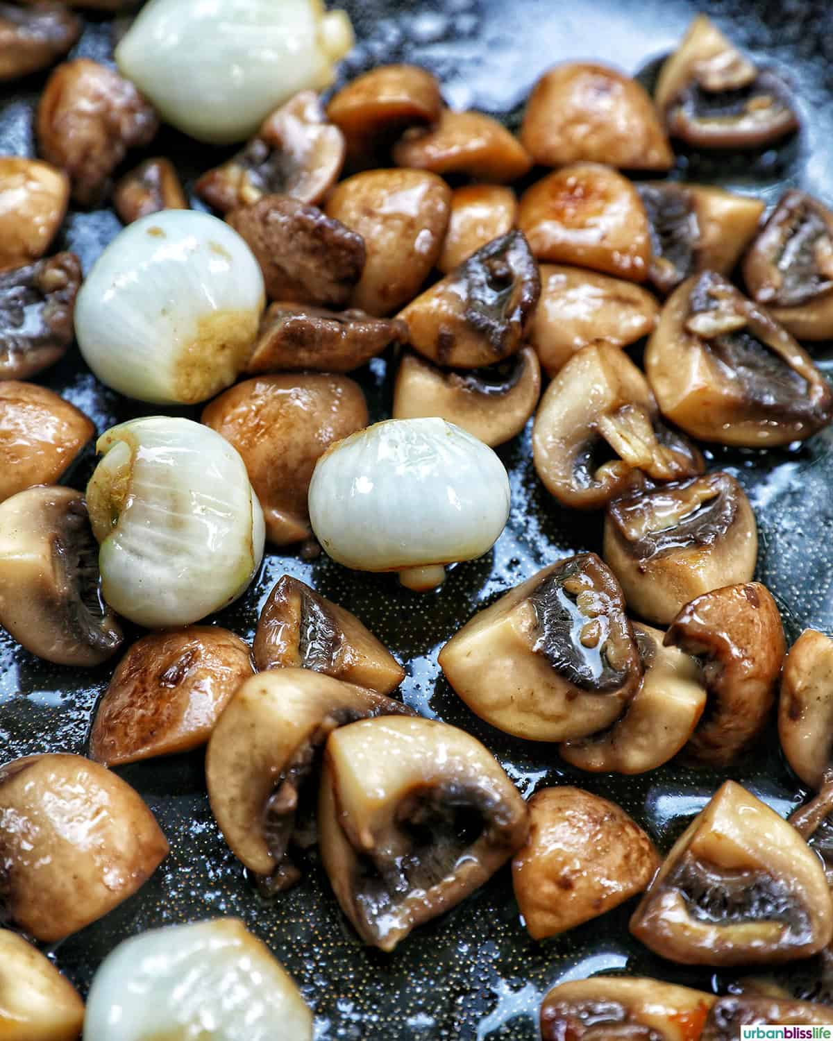 mushrooms and pearl onions in a skillet.
