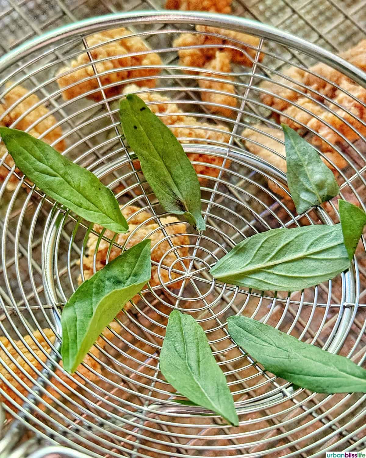 basil leaves in a kitchen spider over a rack of Taiwanese popcorn chicken.