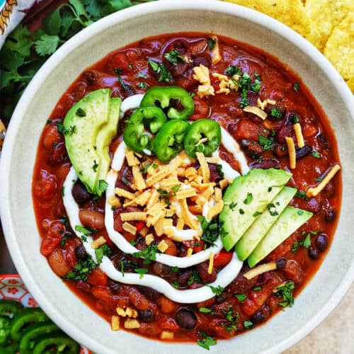 bowl of vegan three bean chili with toppings.