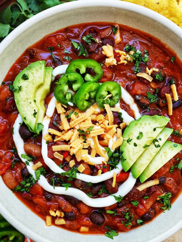 bowl of vegan three bean chili with toppings.