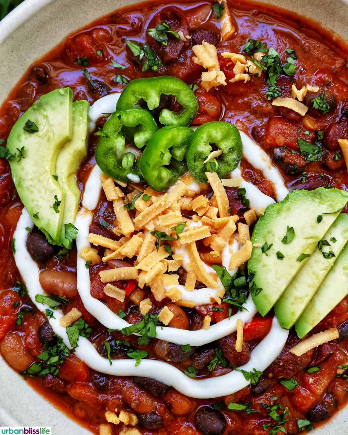 bowl of vegan three bean chili with toppings.
