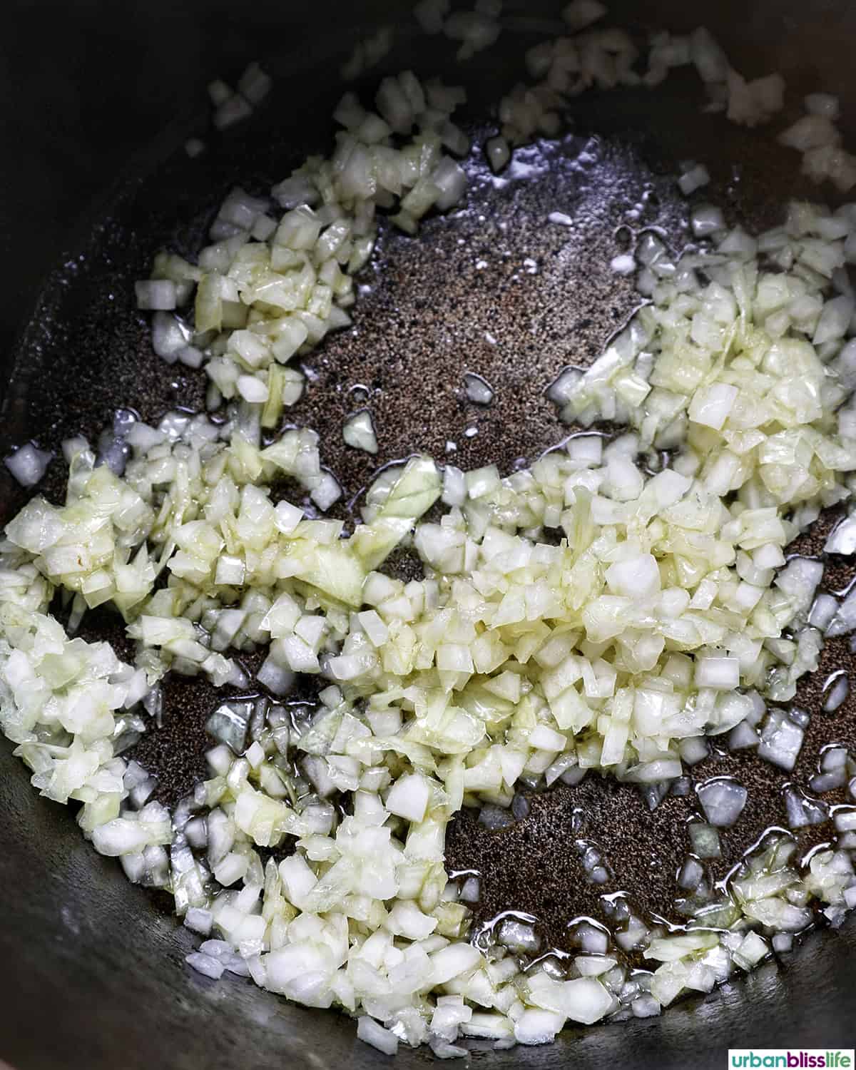 onions and garlic cooking in a pot to make vegan three bean chili
