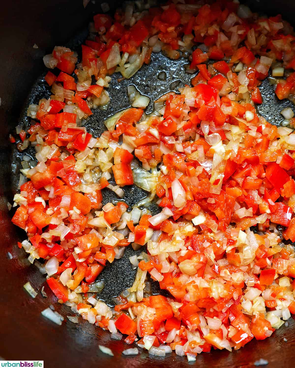 red peppers, onions, and garlic cooking in a pot to make vegan three bean chili
