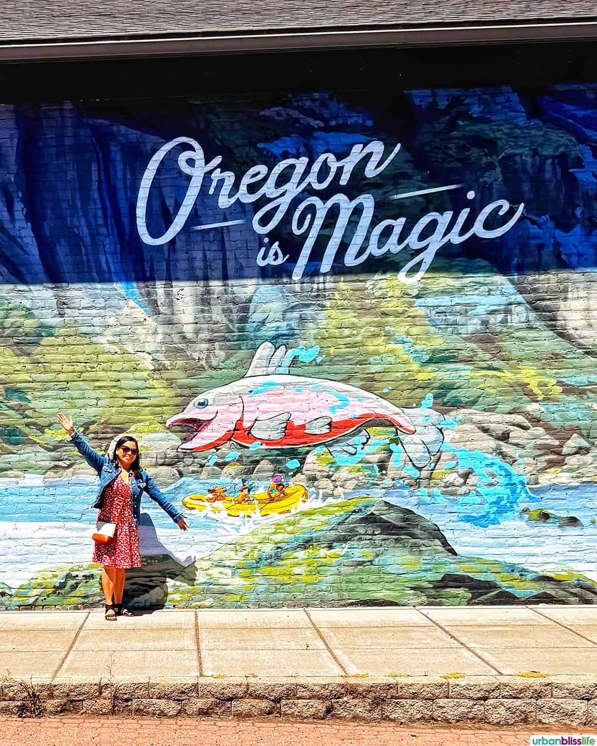 Marlynn Jayme Schotland standing in front of an Oregon is Magic mural.